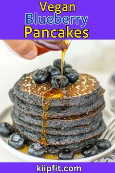 a stack of blueberry pancakes with syrup being drizzled on top