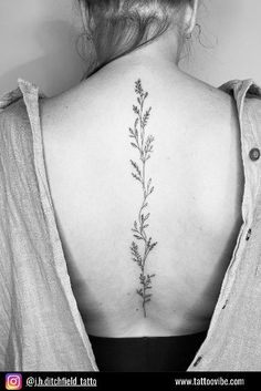 the back of a woman's neck is shown with a flower tattoo on it