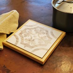 a wooden frame sitting on top of a table next to a pot and cloths