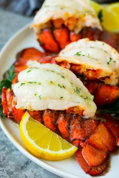 garlic butter lobster tails on a plate with lemon wedges