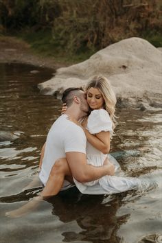 a man and woman are sitting in the water with their arms wrapped around each other