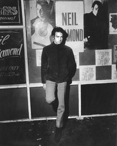 a man standing in front of a wall with posters on it