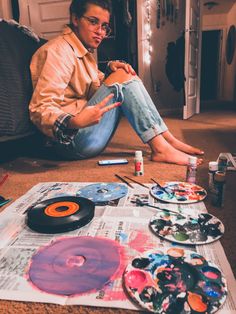 a man sitting on the floor next to some cds