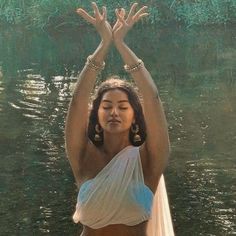 a woman standing in the water with her hands up