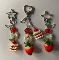 three strawberry shaped keychains with different designs on them, one has a slice of cake and the other has a star