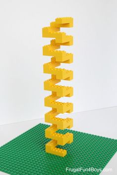 a lego structure made out of yellow blocks on top of a green mat and white wall