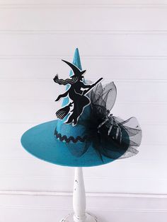 a blue hat with a black and white fairy on the top is sitting on a stand