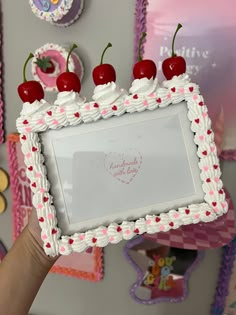 a person holding up a cake with cherries on it