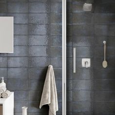 a bathroom with gray tiles and white fixtures on the wall, along with a towel rack