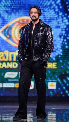 a man standing on top of a runway wearing black pants and a jacket with sequins