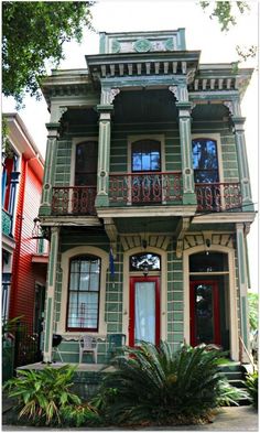 an old victorian style house with red doors and balconies on the second floor