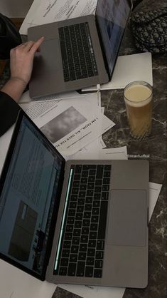 three laptops are on a table with papers and drinks