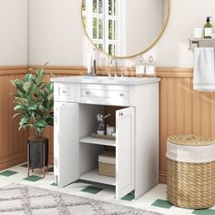 a bathroom with a white vanity, mirror and basket on the floor next to it