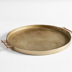 a round brass tray with handles on a white background, set against a plain backdrop