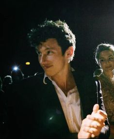 a man and woman standing next to each other in front of a crowd at an event