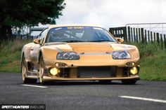 a yellow sports car driving down the road