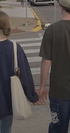 two people walking down the street holding hands