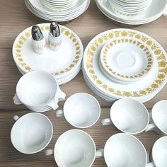 a table topped with lots of white plates and bowls covered in gold trimmings