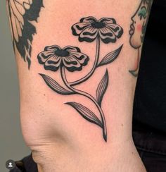 a black and white flower tattoo on the side of a woman's right leg