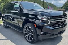 the new chevrolet suburban suv is parked in a parking lot near other cars and trees