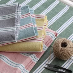 a pile of folded towels sitting on top of a table next to a pair of scissors