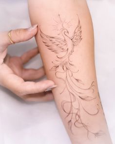 a woman's arm with a bird tattoo on it