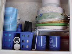 there are many cups and bowls in the cupboard