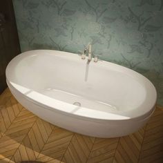 a white bath tub sitting on top of a wooden floor next to a green wall