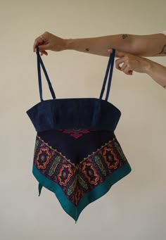 a woman's hand holding up a blue bag with an intricate design on it