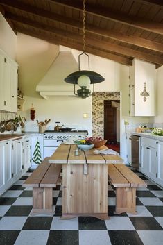 a kitchen with checkered flooring and white cabinetry has an island in the middle