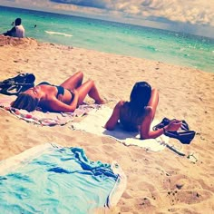 two women in bikinis laying on the beach