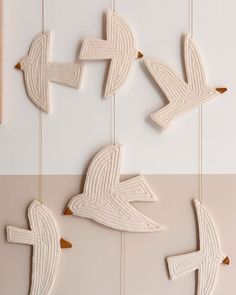 three birds are hanging on the wall and one is made out of wood, while the other has yarn