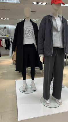 two mannequins are standing on display in a clothing store, one is wearing a red hat