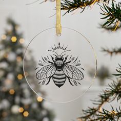 a glass ornament with a bee on it hanging from a christmas tree branch