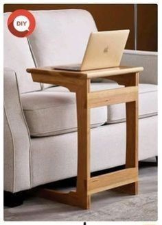 a laptop computer sitting on top of a wooden table next to a white couch in a living room