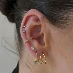 a woman wearing three different types of ear piercings