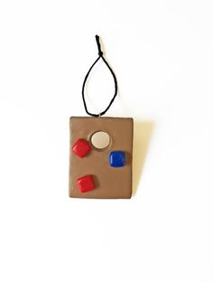 a brown and red object hanging from a string on a white wall next to a black cord