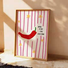 a red hot pepper on pink and white striped paper with stars in the background, framed by a wooden frame