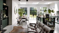 a living room filled with furniture next to a kitchen and dining room table covered in potted plants