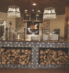 a kitchen with wood stacked on the counter and chandelier hanging from the ceiling