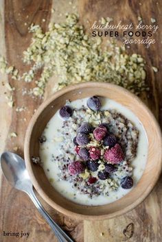 a wooden bowl filled with oatmeal and raspberries next to a spoon