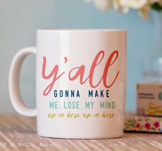 a coffee mug with the words y'all on it sitting next to some flowers