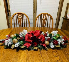 a wooden table topped with a christmas centerpiece on top of a wooden dining room table