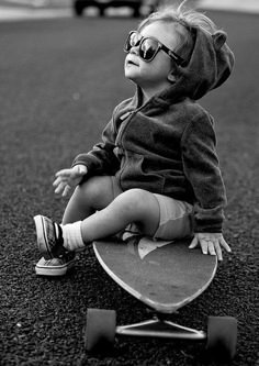 a little boy sitting on top of a skateboard in the middle of the road