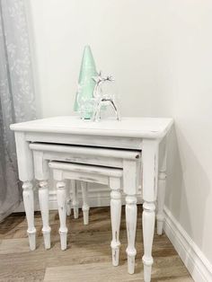 two white tables sitting on top of each other in a room with wood flooring