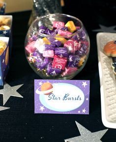 a table topped with lots of different types of candies next to star shaped plates