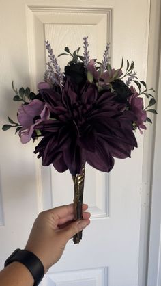 a person holding a purple flower in front of a door