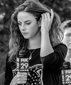 a woman holding a microphone in front of her head while standing next to other people