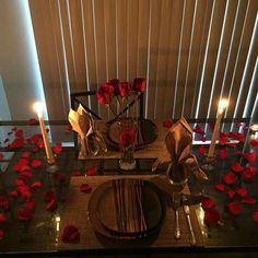 the table is set with rose petals and candles