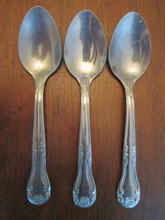 three silver spoons sitting on top of a wooden table